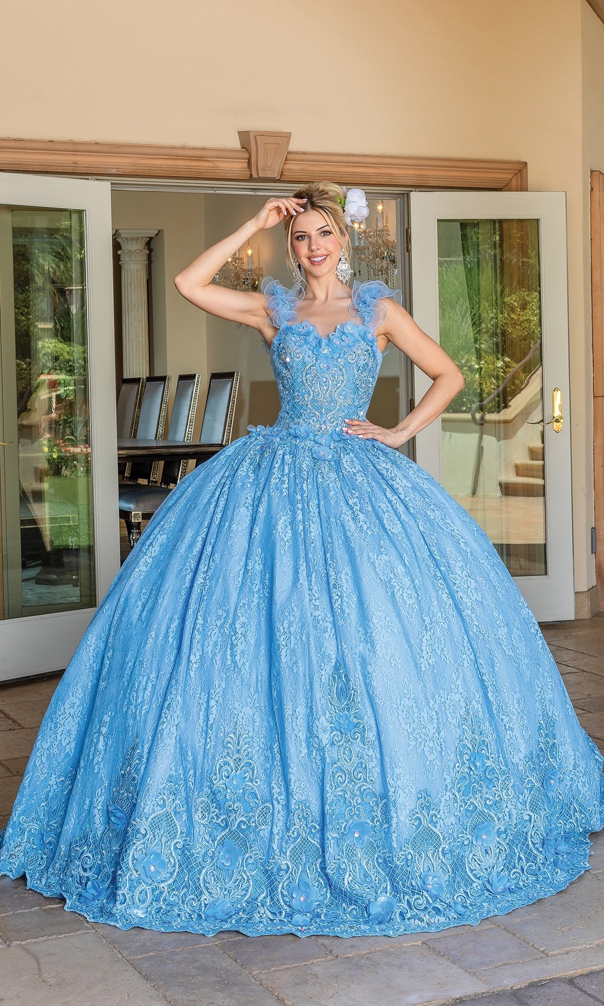 A woman stands outside in front of glass doors wearing Quinceanera Dress 1721 By Dancing Queen, featuring a light blue ball gown with a full skirt, floral lace details, and a romantic sweetheart neckline.